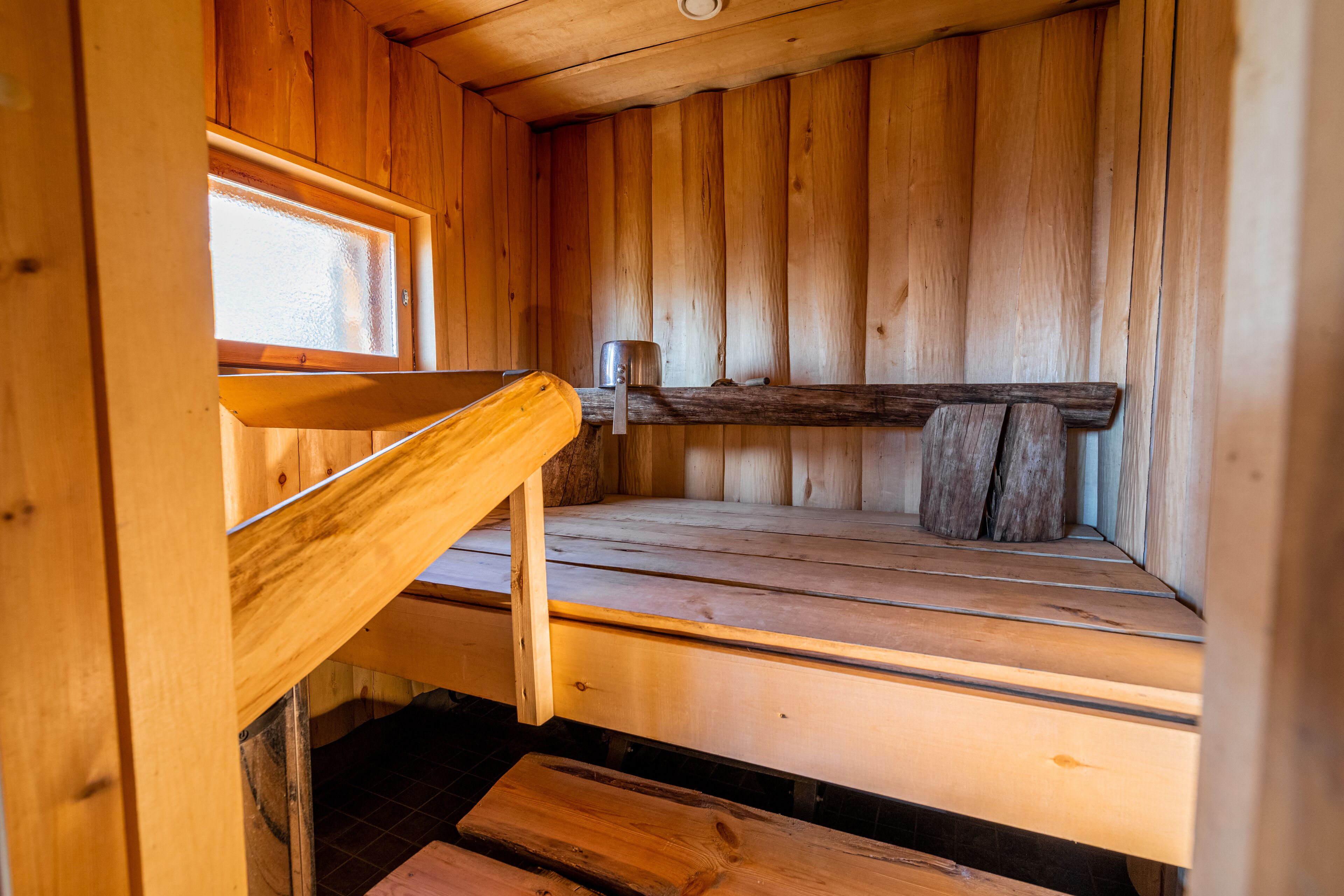 Un sauna en bois avec un banc, une étagère et une fenêtre.