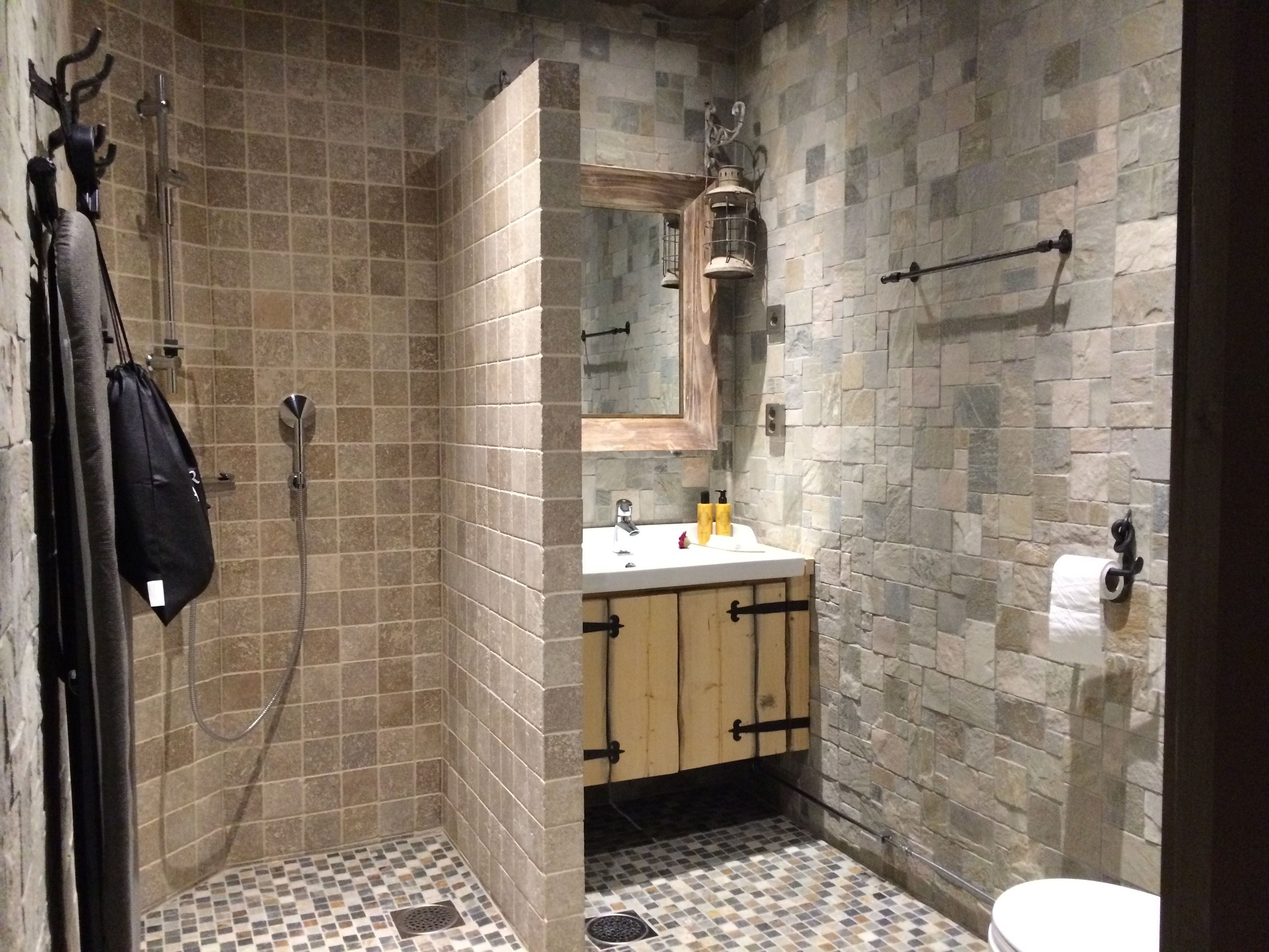 A bathroom with a shower, a sink with toiletries, and a toilet.