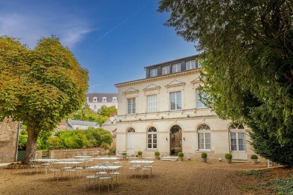A historic building with a courtyard, outdoor seating, and mature trees.