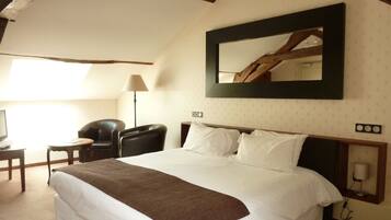 A hotel room with a large bed, a desk with a chair, a lamp, and a mirror on the wall.