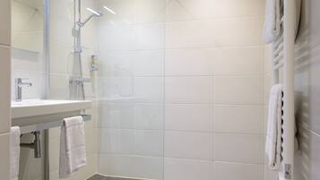 Une salle de bain moderne équipée d’une douche, d’un lavabo et d’un porte-serviettes.