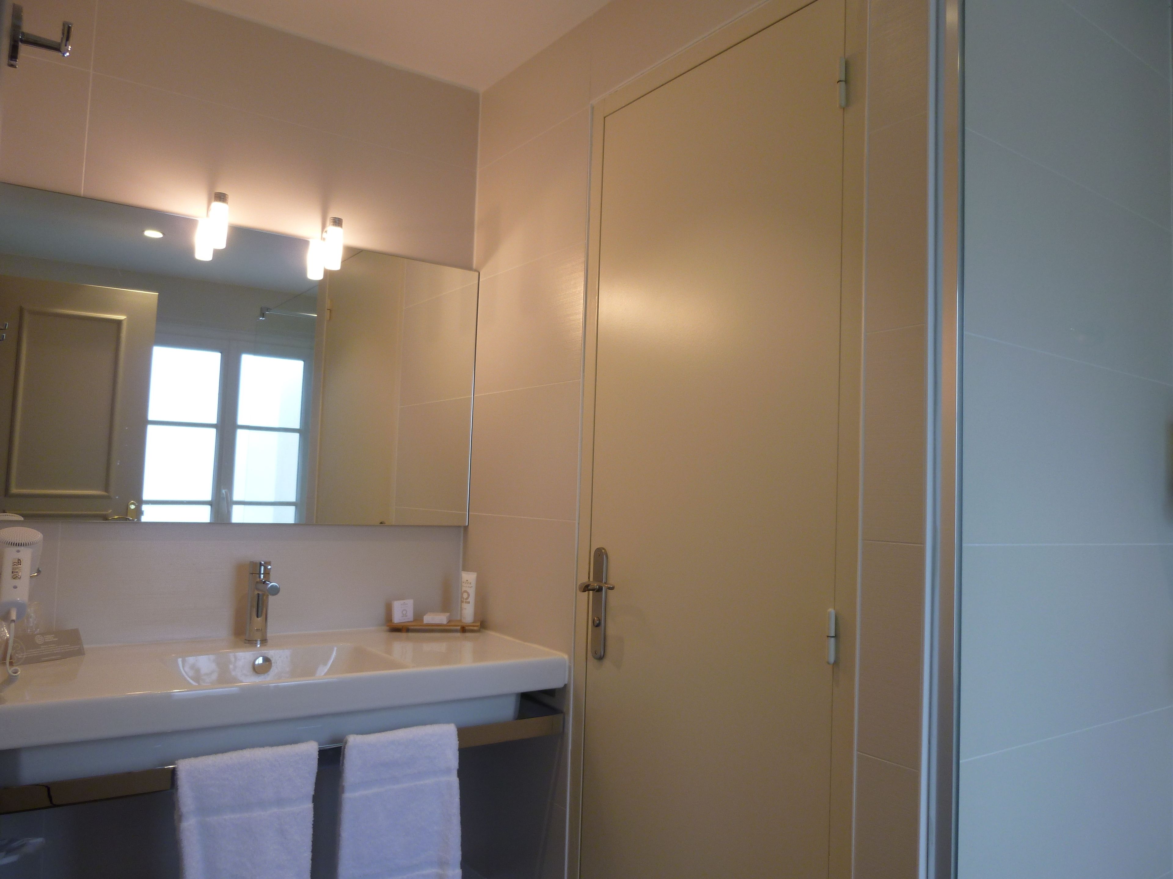 Une salle de bain équipée d’un lavabo, d’un miroir et d’un porte-serviettes.