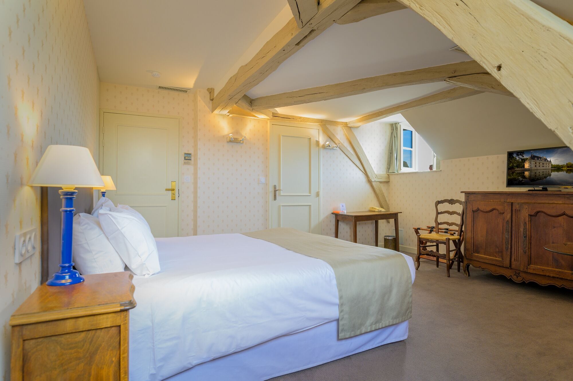 Een slaapkamer met een groot bed, een houten kast, een stoel en een bureau.