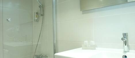A modern bathroom with a glass-enclosed shower, a white sink, and a mirror above the sink.