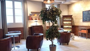 A cozy interior with leather seating, a central potted plant, a wine rack, and a menu board.