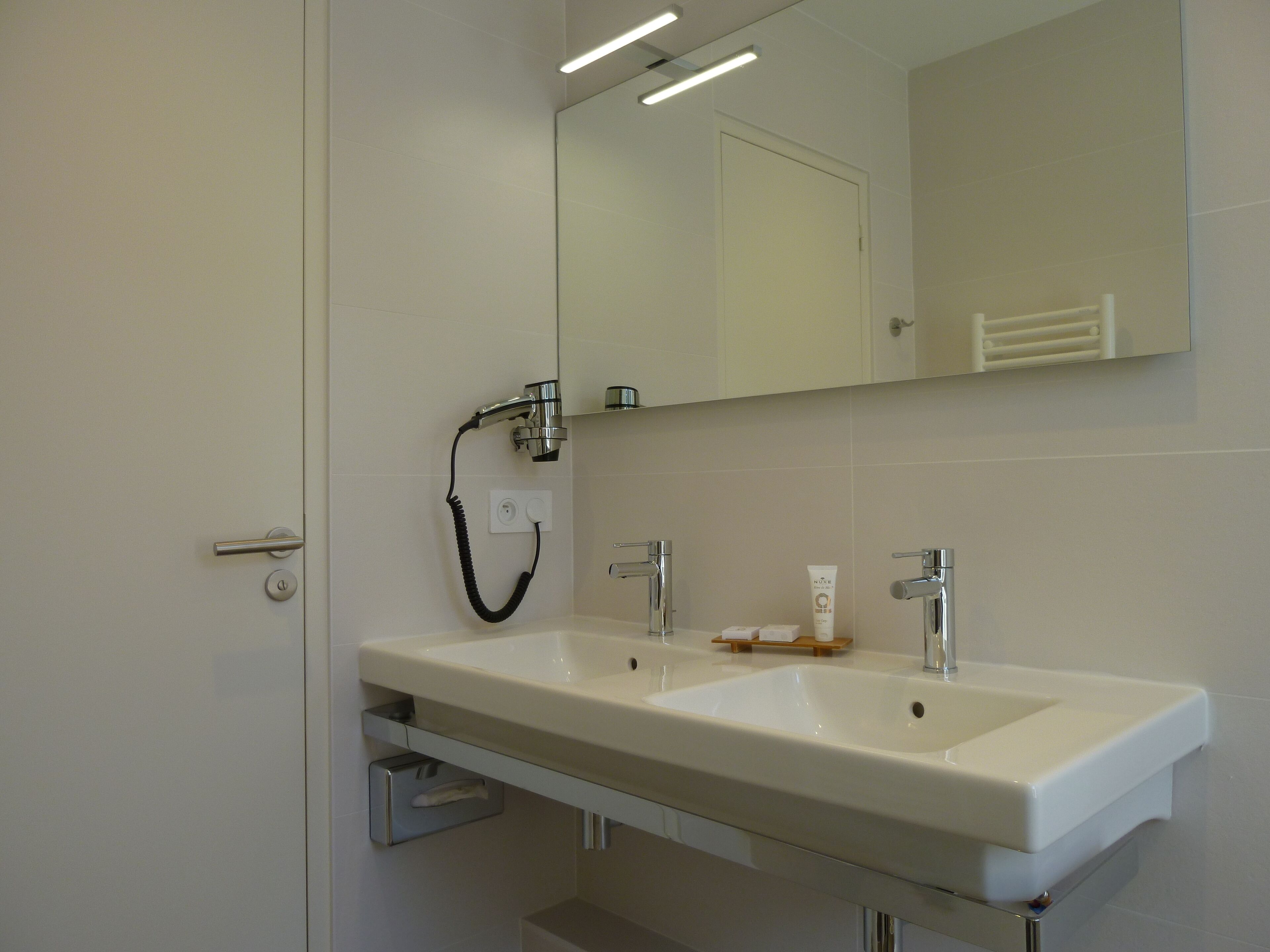 A bathroom with a white sink, a mirror, and a handheld showerhead.