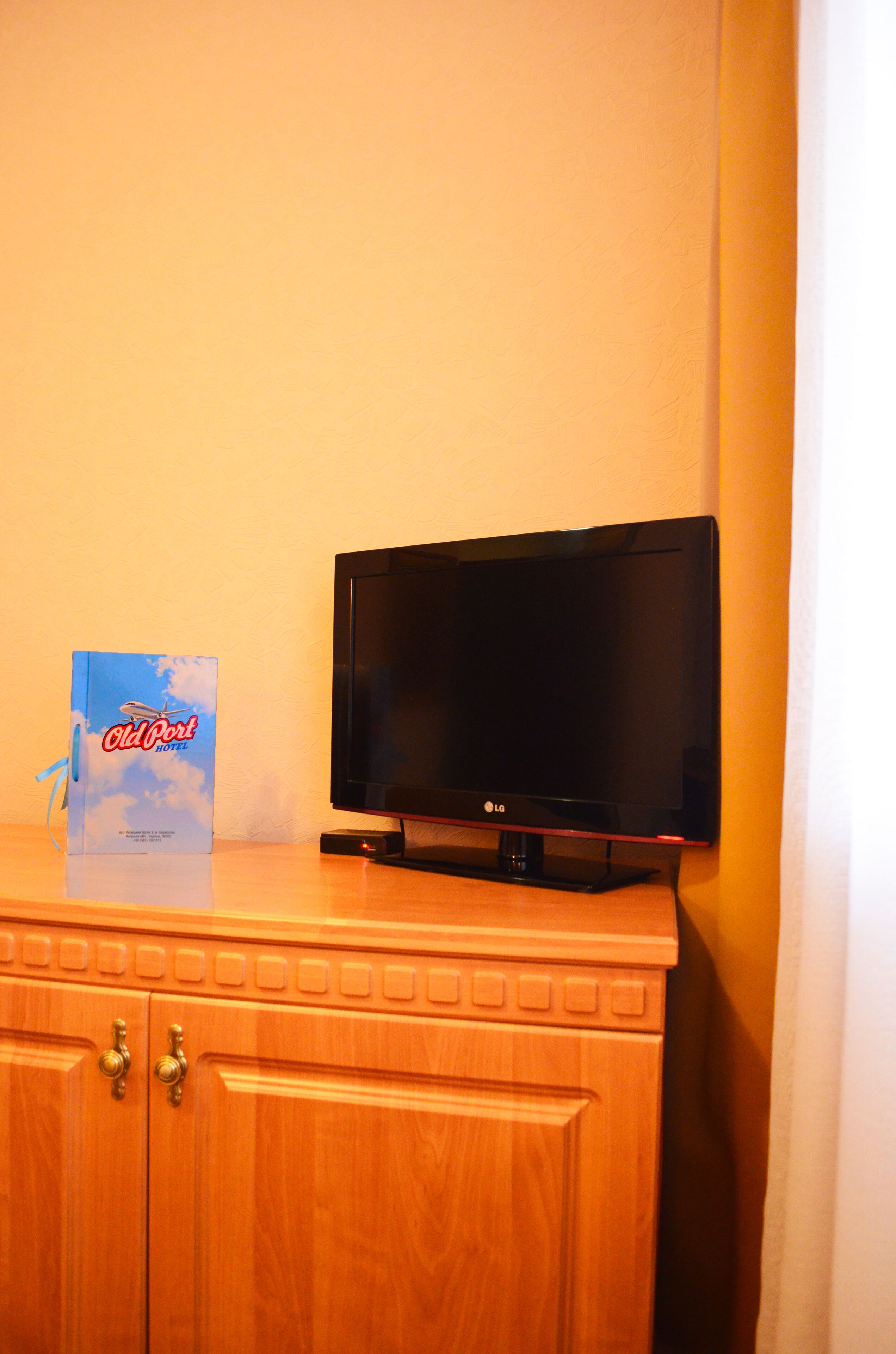 Un televisor sobre un mueble de madera con un libro titulado 'Old Port Hotels' a su lado.