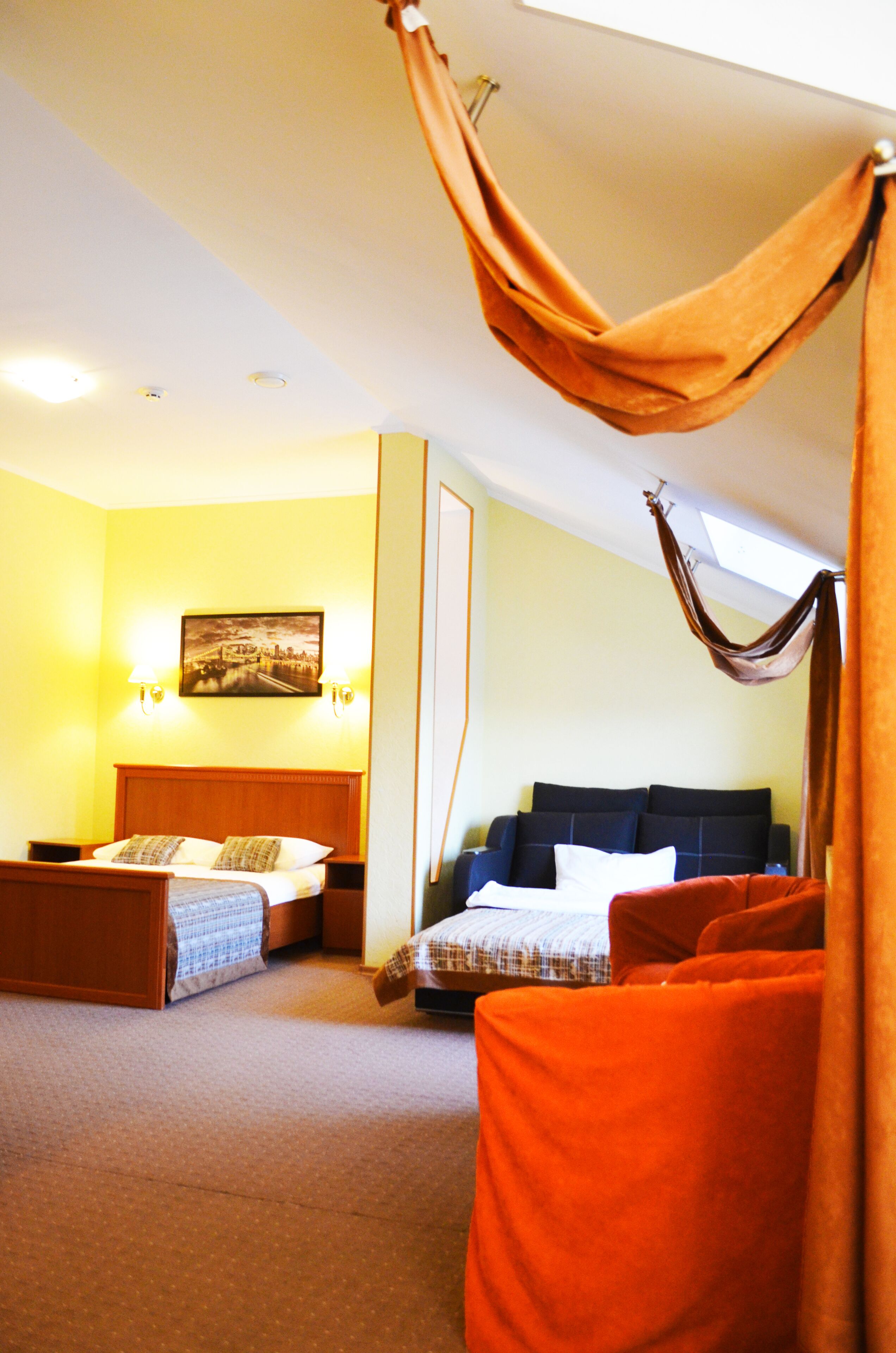 A hotel room with two beds, a large window, and a painting on the wall.