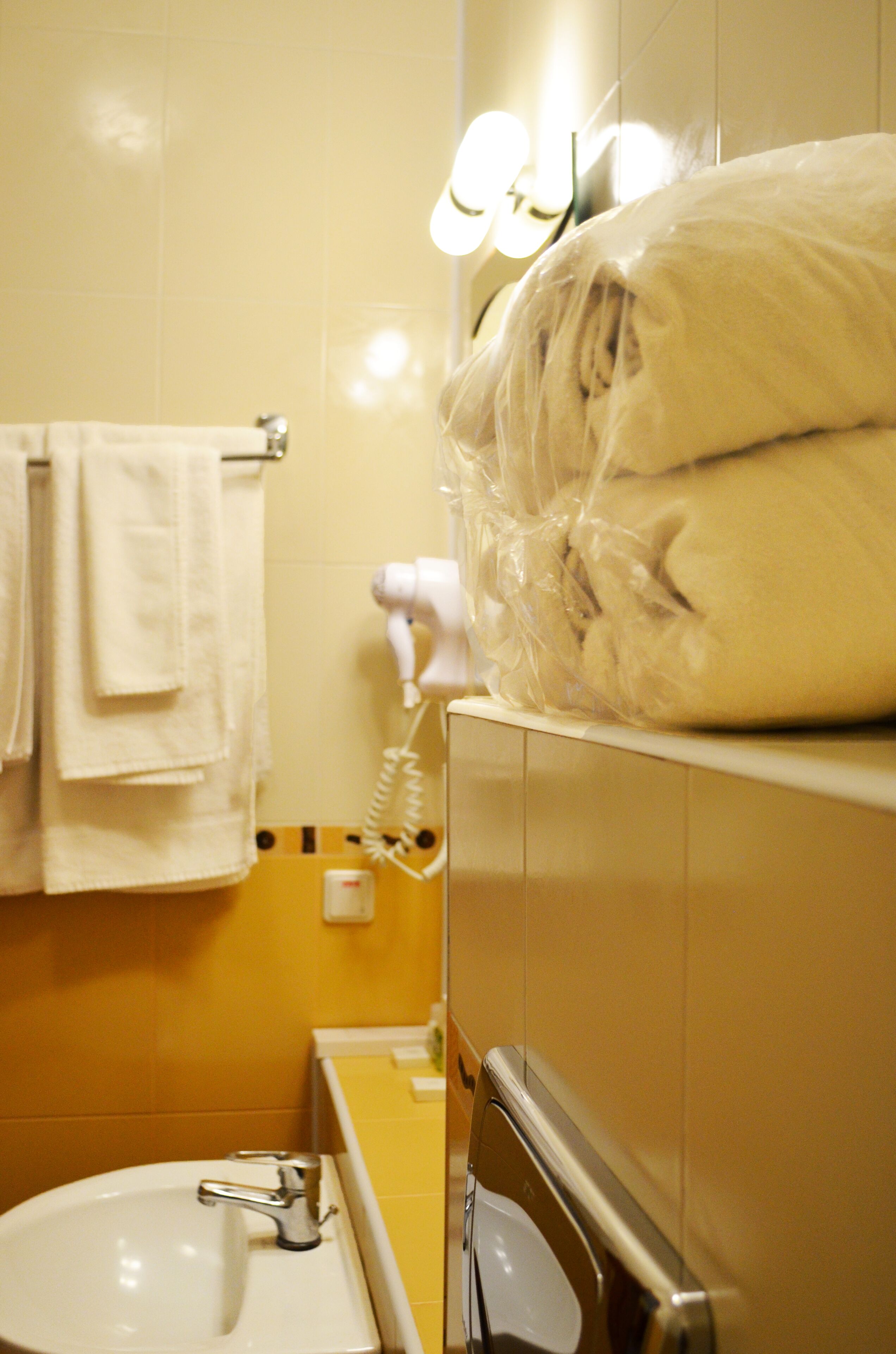 Un bagno con lavandino, portasciuga asciugamani e phon su un ripiano.