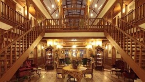 A spacious library with a high ceiling, wooden bookshelves, a central table with chairs, and a staircase connecting two levels. - Kerme Ottoman Palace - Boutique Class (Ula)