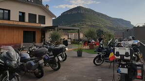 A hotel with a sign, motorcycles parked in front, and a mountainous backdrop. - Hôtel  la Capelle (Millau)