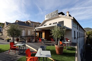 Un hotel con mesas al aire libre, una señal que indica que es un hotel y vistas de los edificios circundantes.