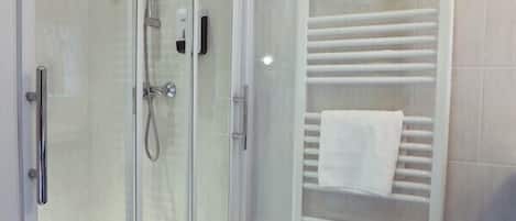 A shower with a glass door, a white towel rack, and a tiled floor.
