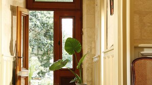 A hallway with a checkered floor, a chandelier, a potted plant, and a door leading outside. - La Porte Rouge - The Red Door Inn Chambres d'Hotes (Saintes)