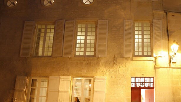 A building with multiple windows, some with shutters, and a door with a metal gate. - La Porte Rouge - The Red Door Inn Chambres d'Hotes (Saintes)
