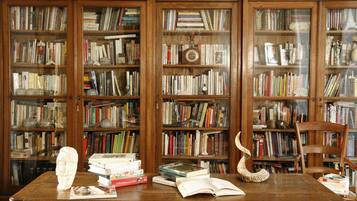 Ein Holztisch mit Büchern, einer Uhr und einer Büstenstatue.