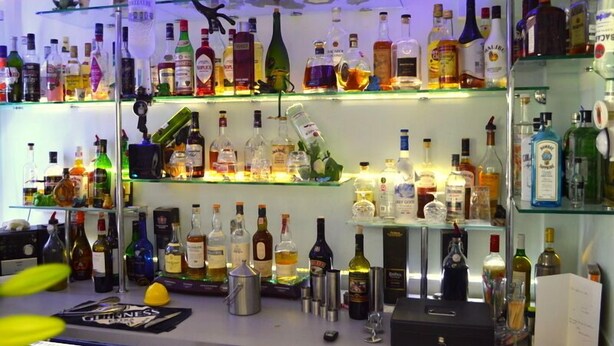 Een barruimte met planken vol verschillende drankflessen.