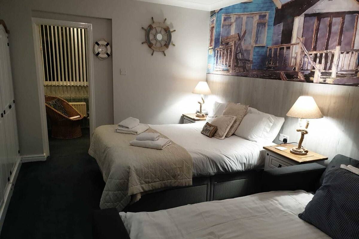 A hotel room with two beds, a large painting on the wall, and a chair in the corner.