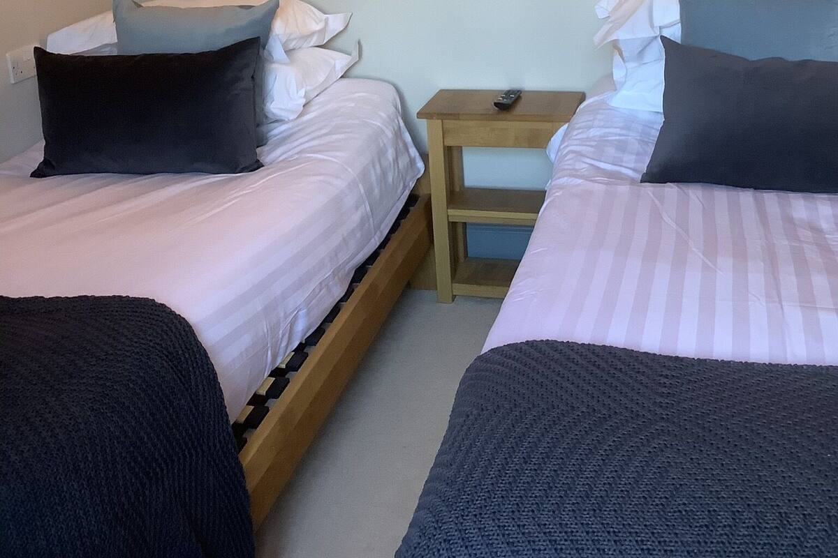 Une chambre avec deux lits, une table de chevet et des lampes fixées au mur.
