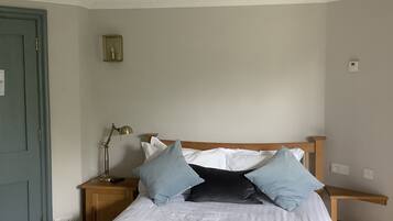 A bedroom with a bed, two bedside tables, a lamp, and a door.