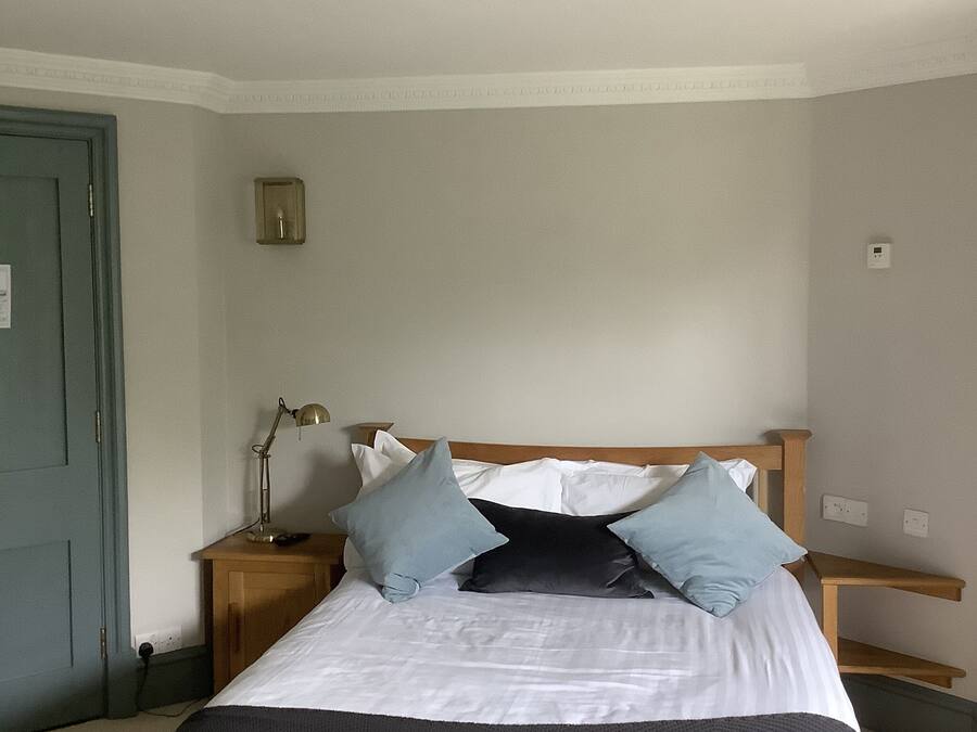 A bedroom with a bed, two bedside tables, a lamp, and a door.