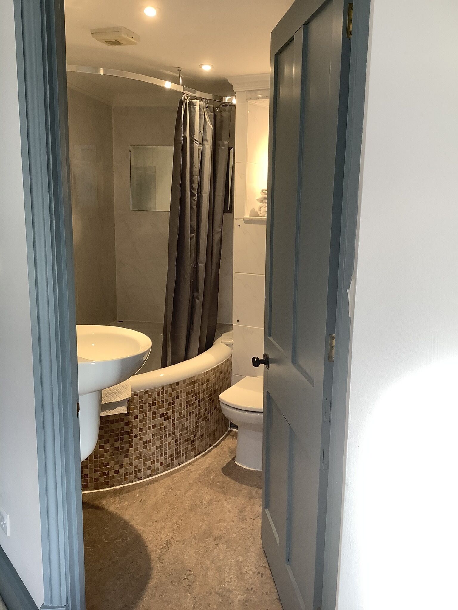 A bathroom with a shower, toilet, and sink.