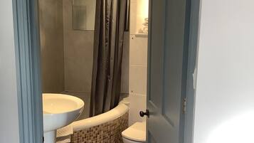 A bathroom with a shower, toilet, and sink.