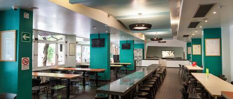 A modern restaurant with long communal tables and individual seating.