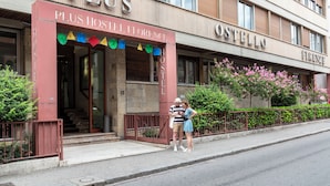 A hotel with a red entrance and the name 'Plus Hostel Florence' above the door.