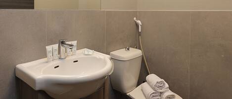 Une salle de bain moderne équipée d’un lavabo, de toilettes et d’un porte-serviettes.