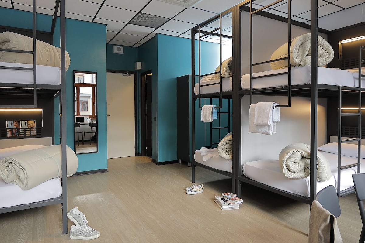 Una habitación de hotel moderna con literas, un espejo y una pequeña mesa con libros.