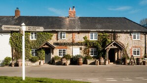 Un bâtiment traditionnel en pierre, agrémenté d’un panneau indiquant les directions vers Shaftesbury et Salisbury.