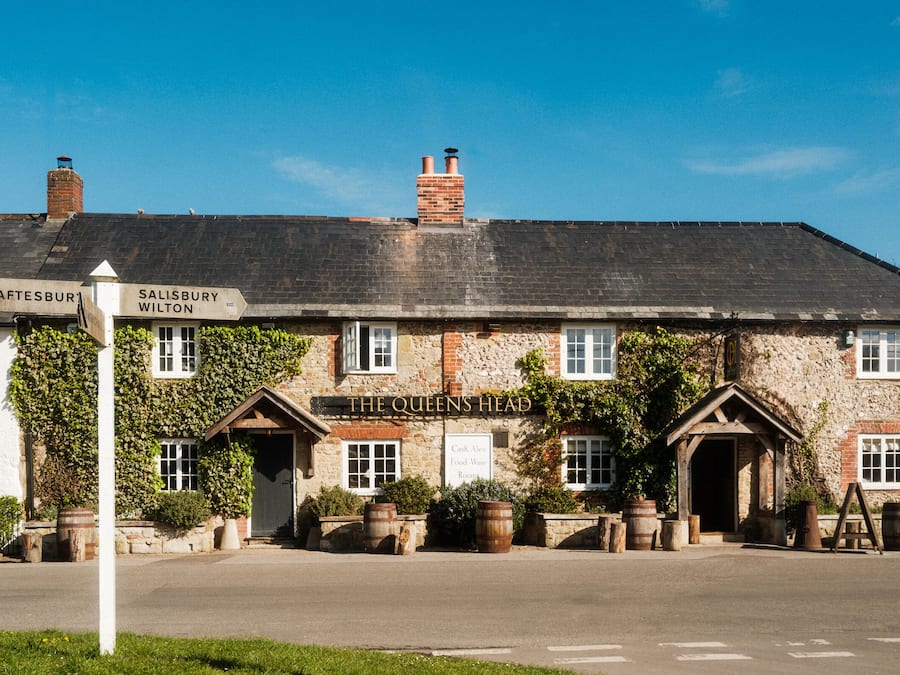 Un edificio in pietra dal fascino tradizionale con una targa che indica le direzioni per Shaftesbury e Salisbury.