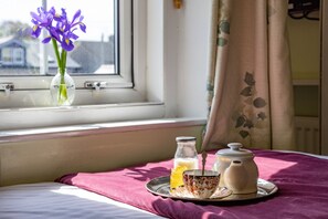 A bed with a pink towel, a tray with a teapot, a milk bottle, and a jar of jam. - Homelands Guest House (Barnard Castle)