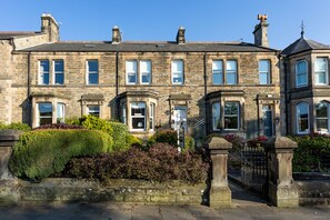 A row of stone townhouses with multiple windows, a gated entrance, and well-maintained hedges. - Homelands Guest House (Barnard Castle)