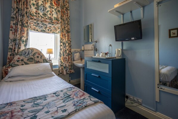 A bedroom with a bed, a dresser, a television, and a window with curtains. - Homelands Guest House (Barnard Castle)