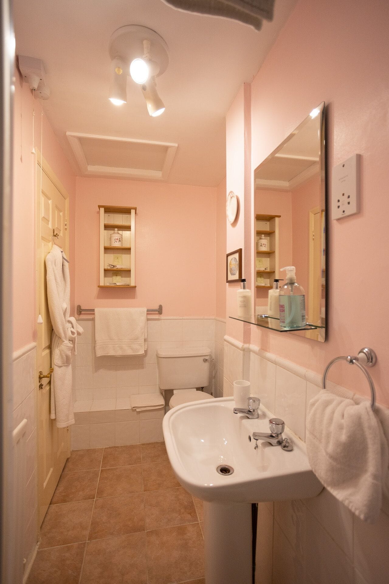 A bathroom with a white sink, a toilet, a mirror, and a towel rack.