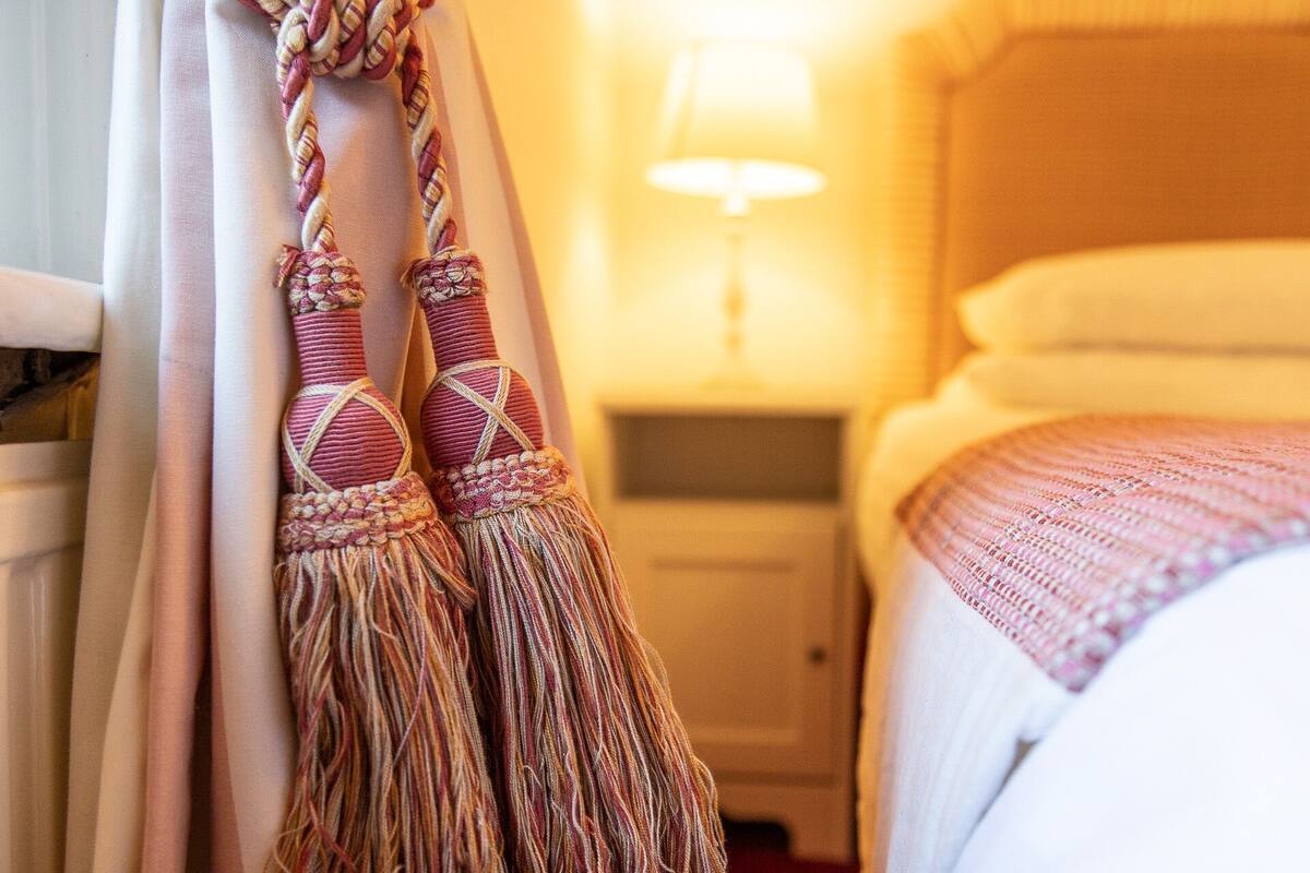 Una habitación de hotel con cama, mesita de noche y lámpara.