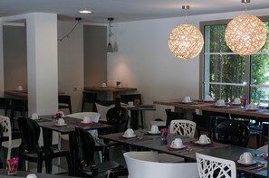 A dining area with tables set for service, chairs, and hanging pendant lights. - Lagrange Apart'HOTEL Montpellier Millénaire (Montpellier)
