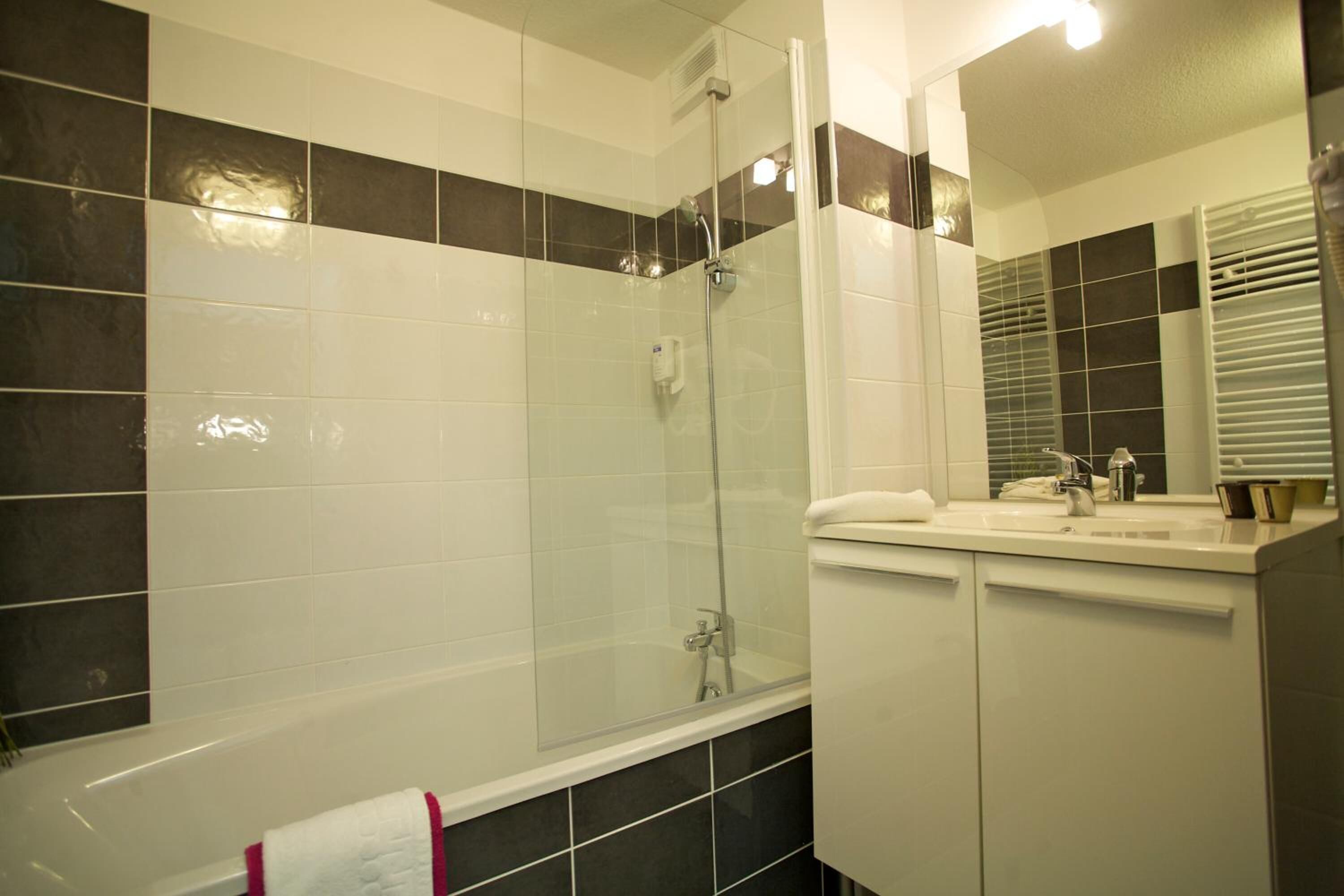Une salle de bain moderne avec une douche à parois de verre, un lavabo blanc et un miroir.