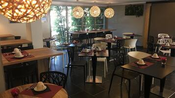 A restaurant with round tables, rectangular tables, and a mix of black and white chairs.