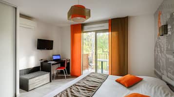 A modern hotel room with a bed, a desk with a laptop, a TV, and a balcony with a chair.