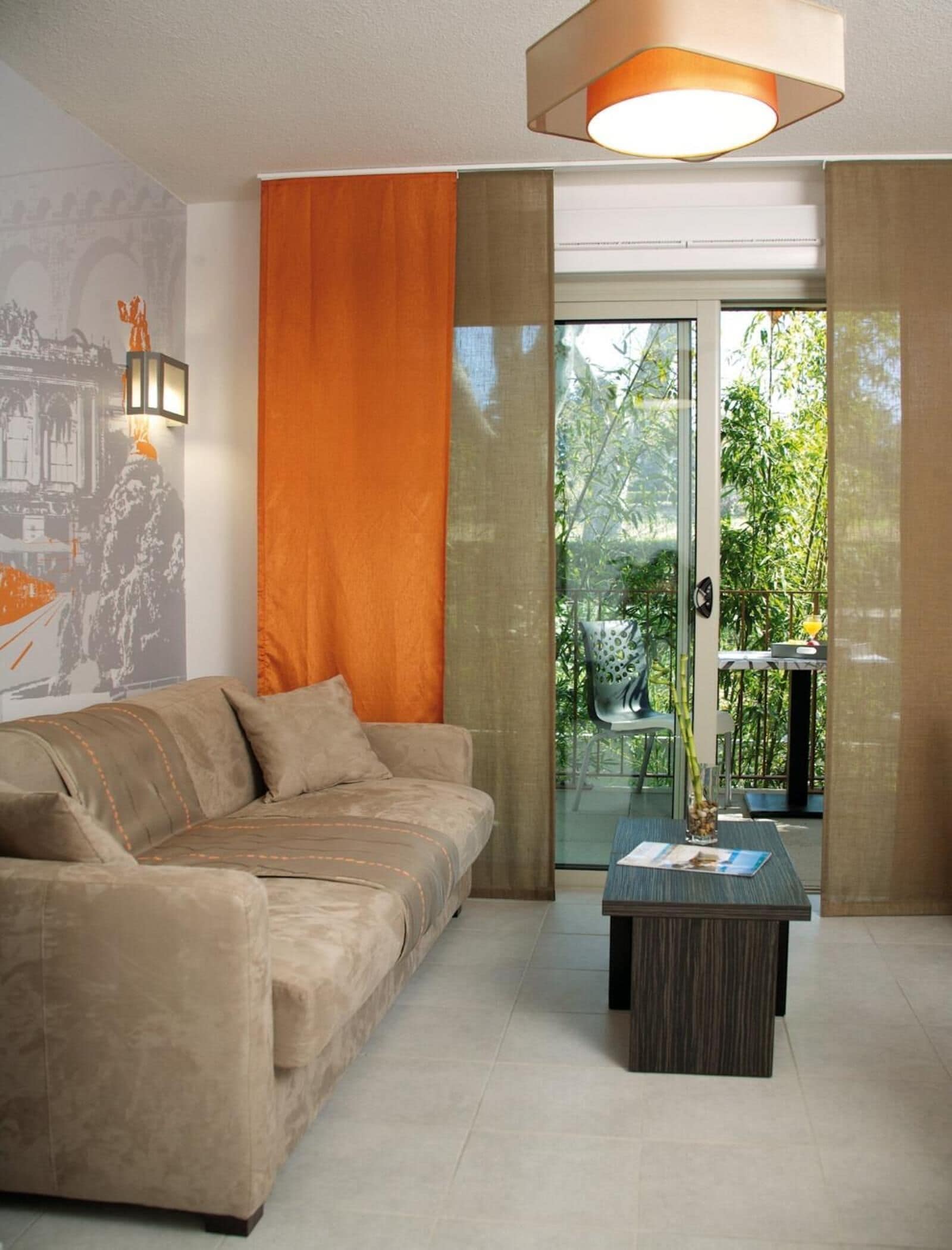 A modern living room with a sofa, a coffee table, and a glass door leading to a balcony.