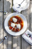 Un postre sobre un plato blanco con cuchara y servilleta en una mesa de madera.