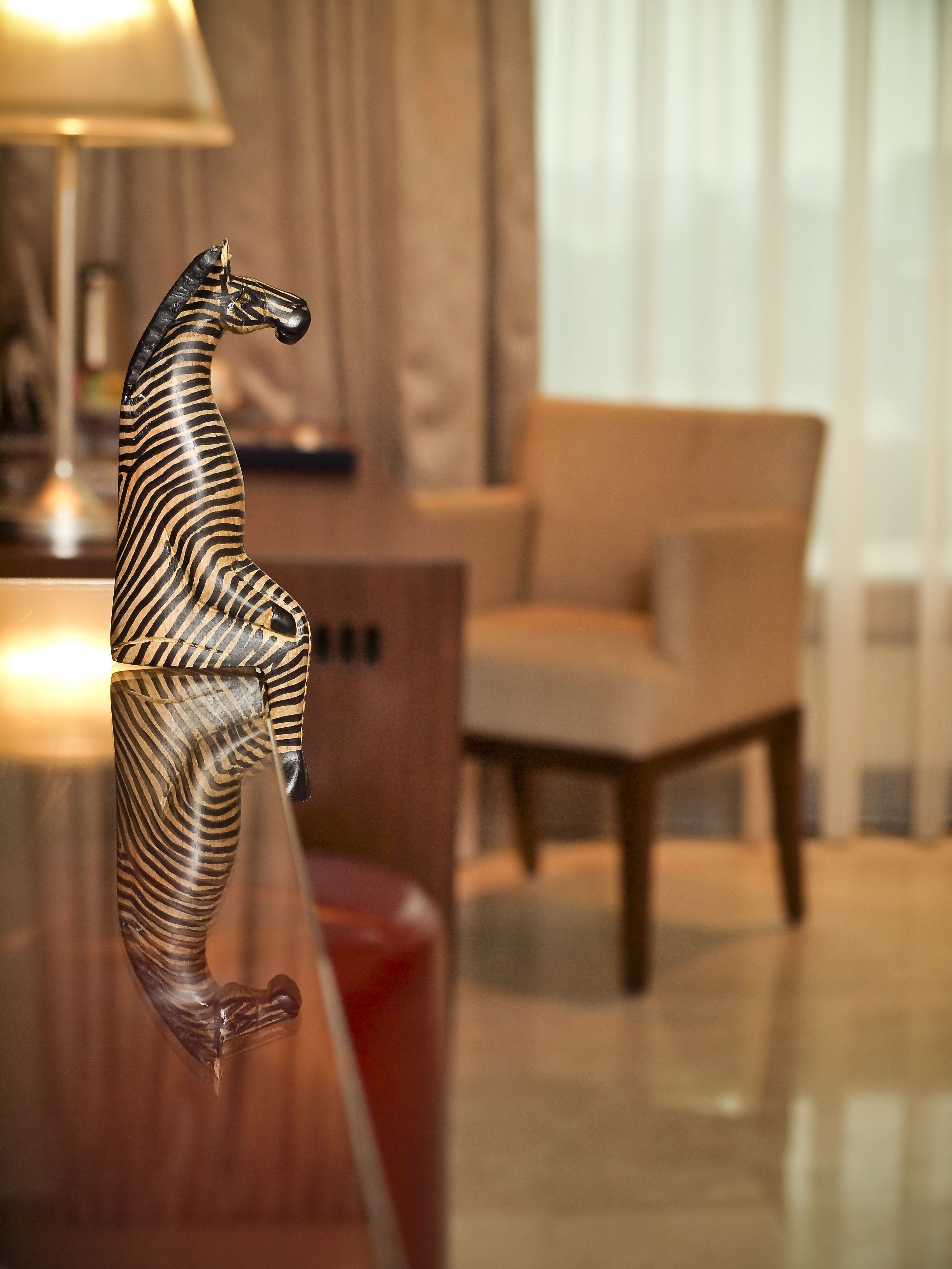 A zebra sculpture in a modern living room with a sofa and a lamp.
