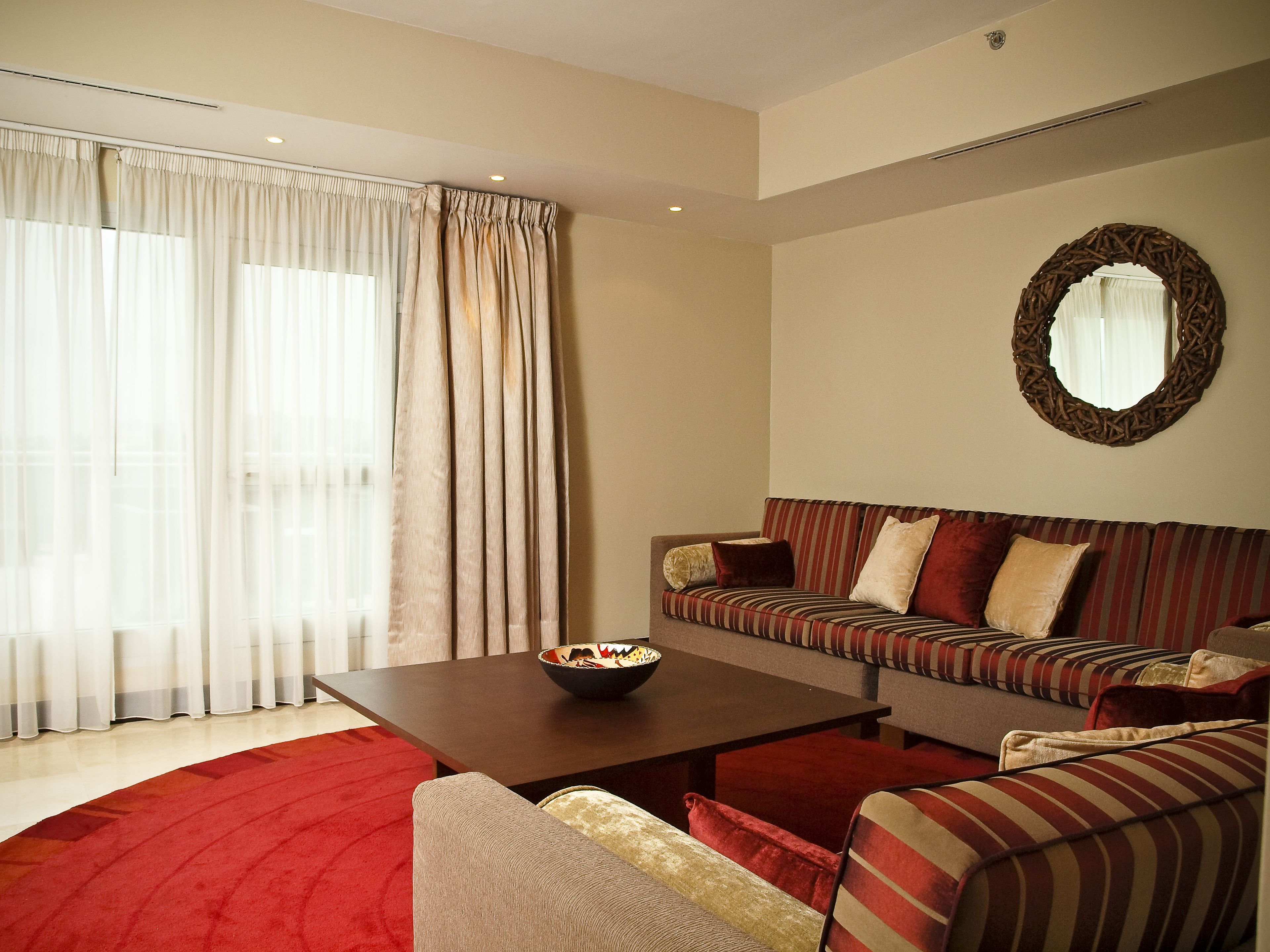 A modern living room with a sofa, armchairs, a coffee table, and a large window with curtains.