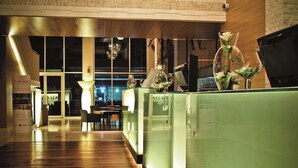 Un hall d’hôtel avec un plancher en bois, des cloisons en verre et un comptoir d’accueil.