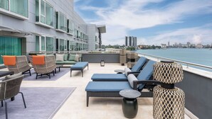 Une terrasse sur le toit, dotée de chaises longues, d’un espace repas et offrant une vue sur le panorama urbain.
