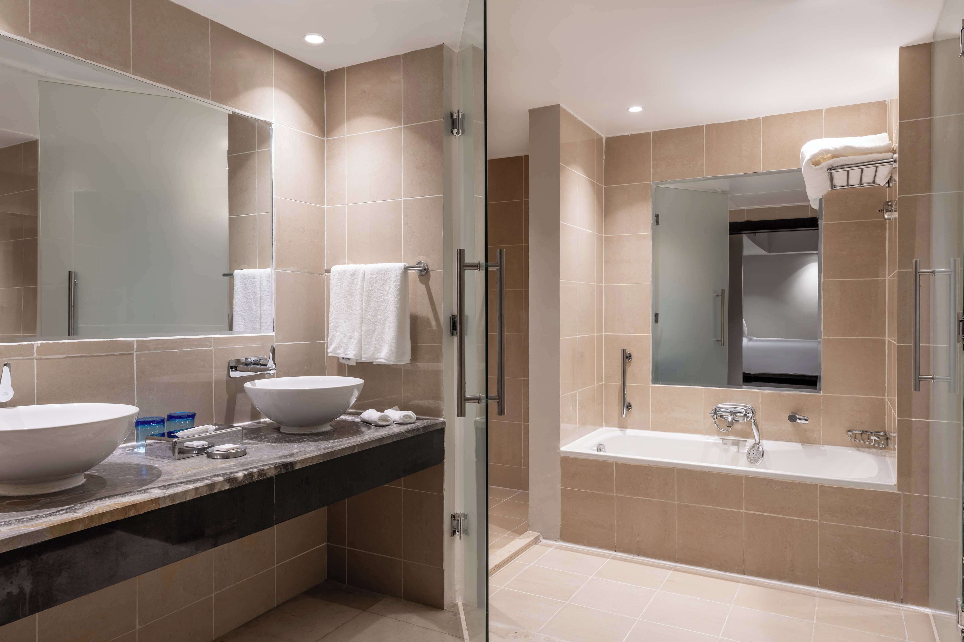 A modern bathroom with a glass-enclosed shower, a large sink, and a bathtub.