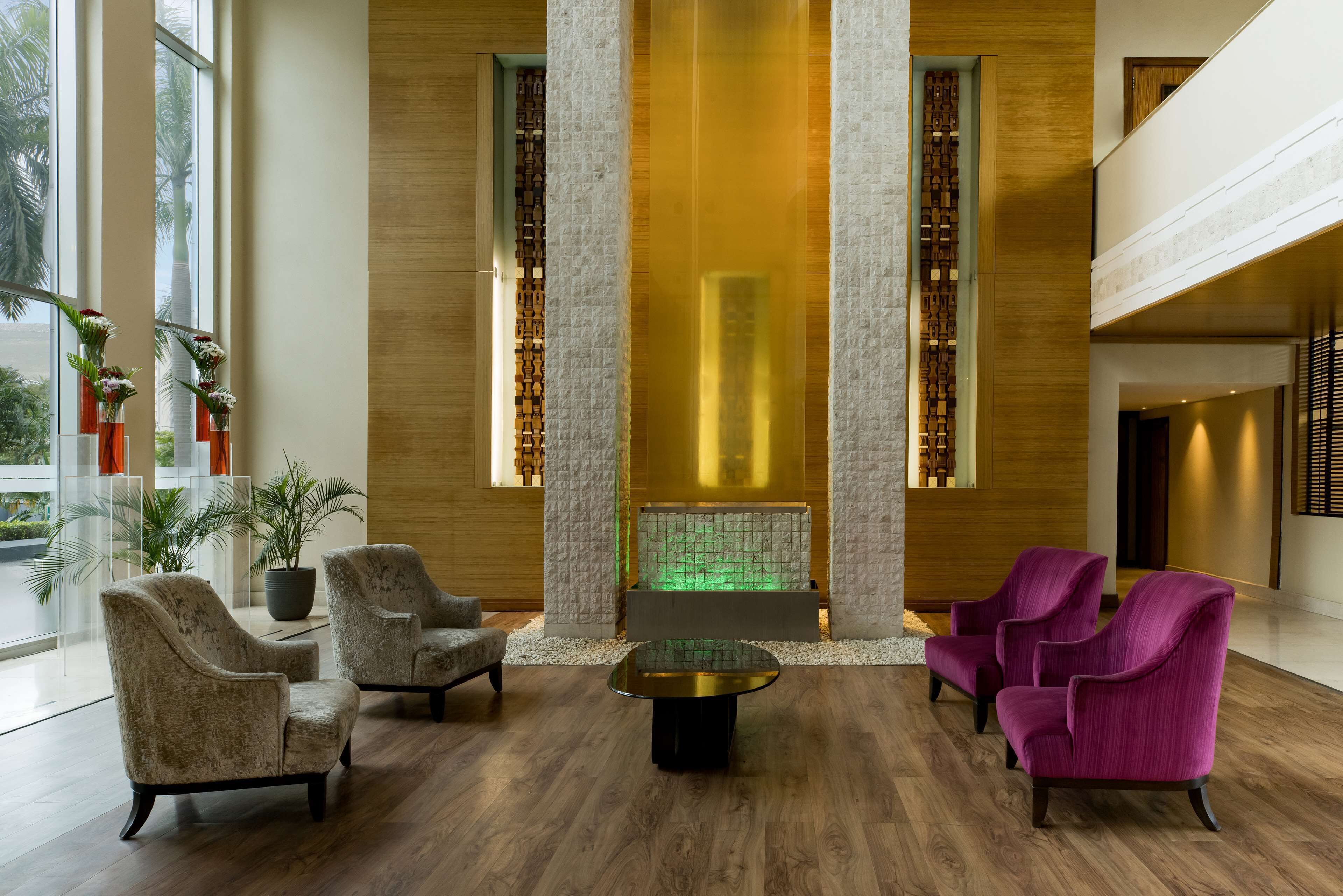 A lobby with a central seating area, a decorative wall, and a large window.